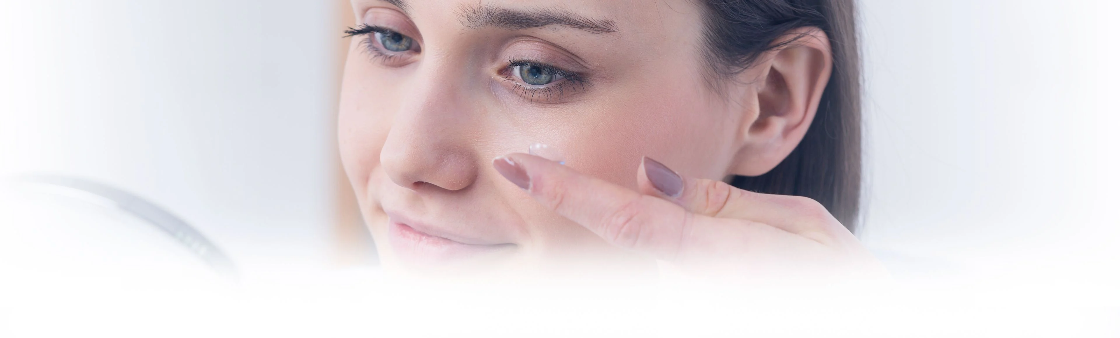  A woman placing a contact lens into her left eye